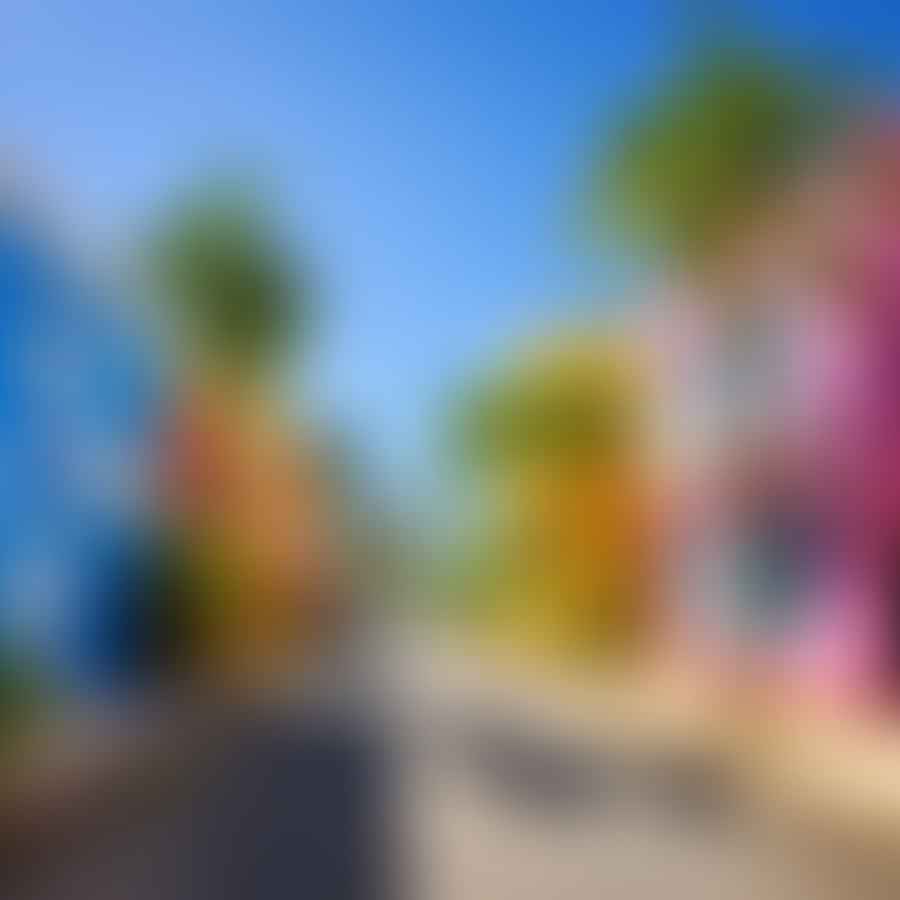 A picturesque Caribbean street with colorful buildings, palm trees, and a clear blue sky